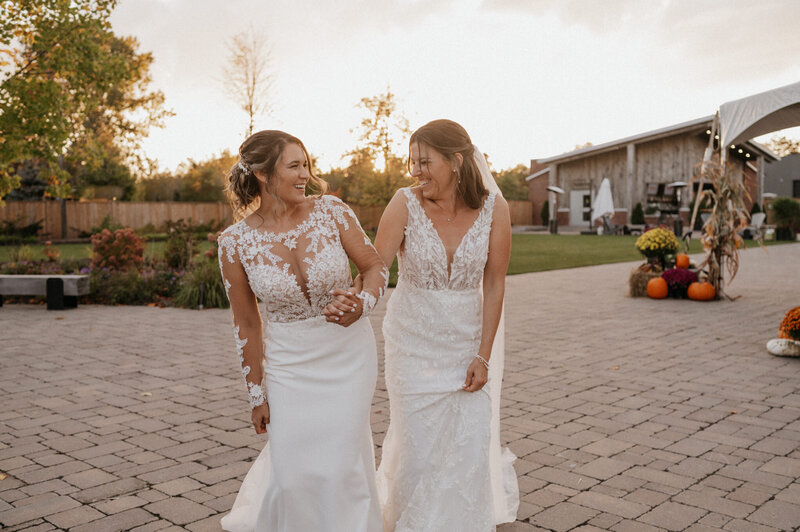 two brides smiling holding hands at Ontario wedding
