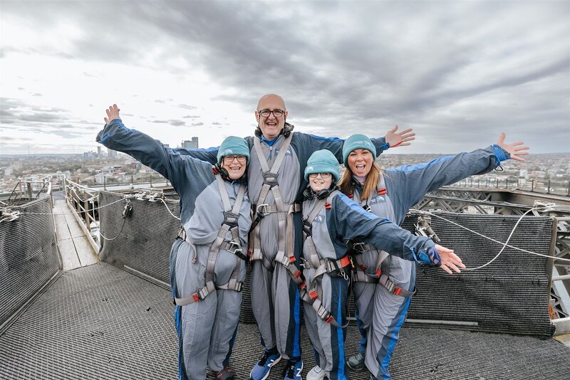 A group of people wearing harnesses celebraint their marriage on top of the Sydney Harbour Bridge