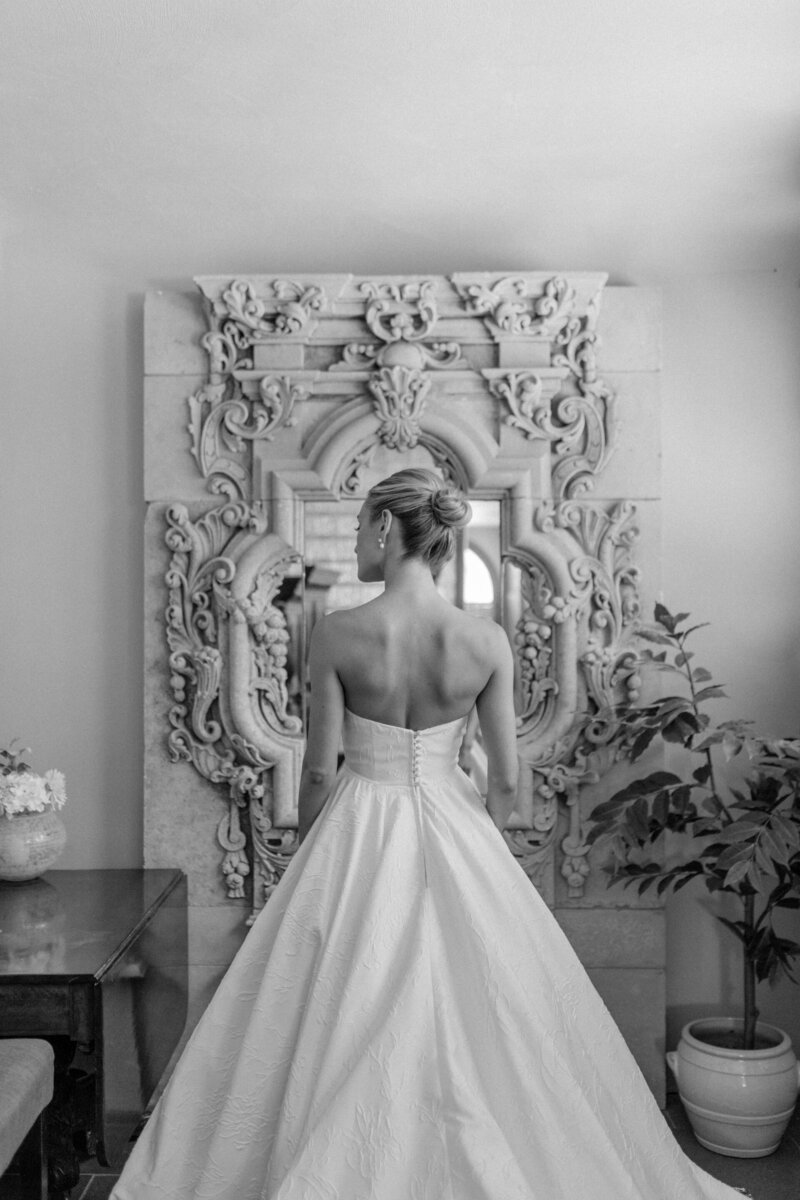 a bride standing in front of a mirror in her wedding dress