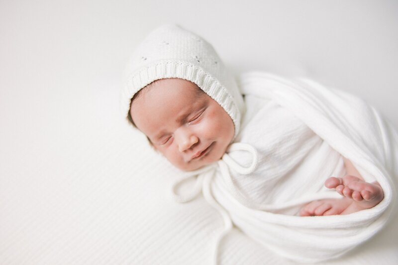 Baby wrapped in white with bonnet by Philadelphia Newborn Photographer