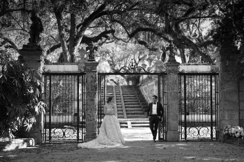 bride and groom leaning up against gate at wedding venue in fort myers florida