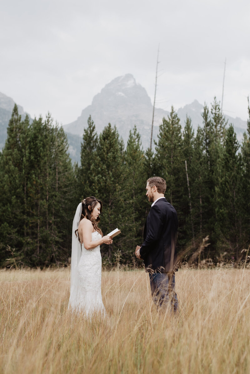 bride and groom have a first look and private vow reading in a field surrounded by the woods with the mountains in the distance for their fall wedding
