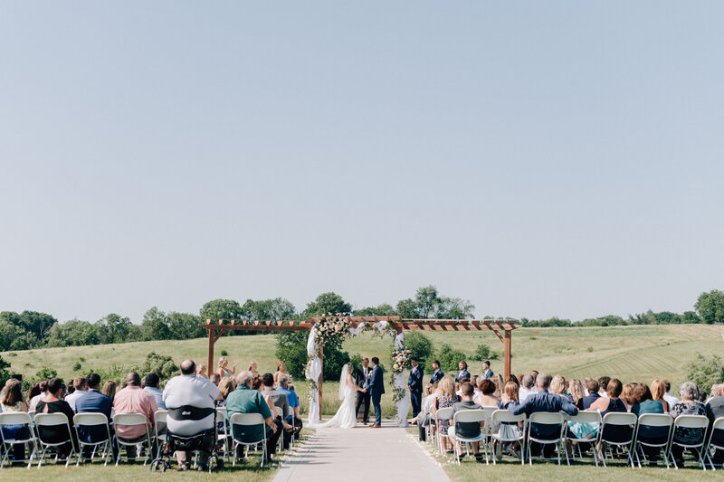 Bride and groom say their vows over the pond at Carper Vineyard and Winery. Photo by Anna Brace, who specialized in Iowa Wedding Photography
