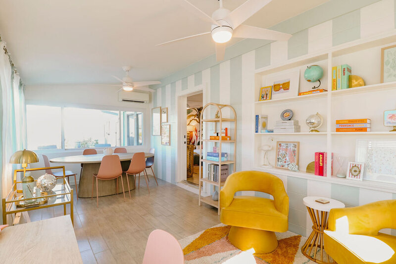 sunroom with striped wallpaper sitting area with yellow chairs