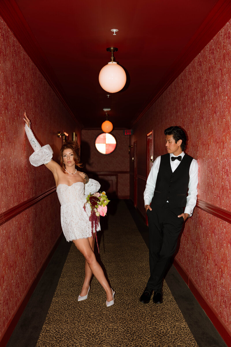 a bride and groom standing in a red vintage hallway