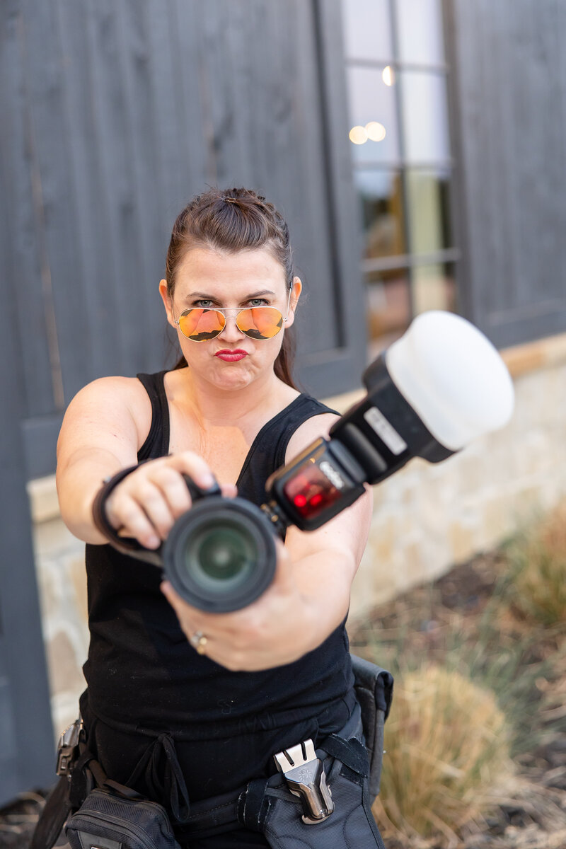 Colorful austin wedding photographer points camera and flash while sporting a badass expression and coral ombre aviator sunglasses