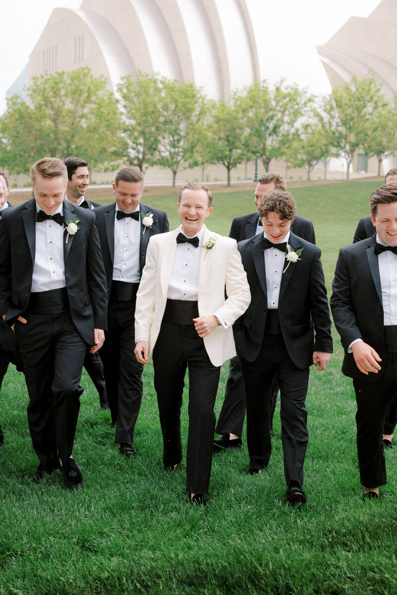white tie groom with groomsmen walking in front of the Kauffman Center for Performing Arts