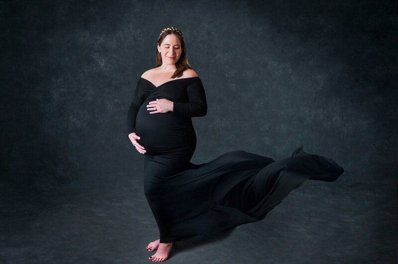 Pregnancy studio portrait mom holding belly with train flowing