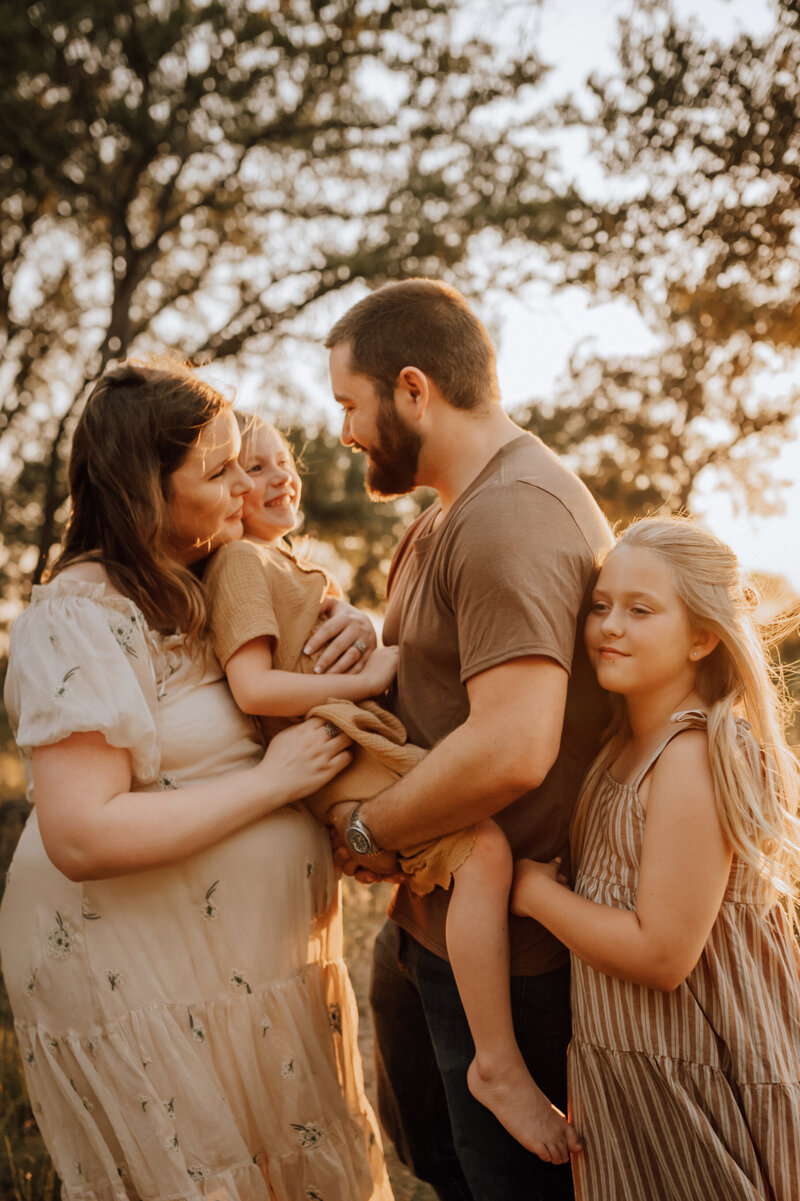 Family of four cuddled up in the golden hour light.