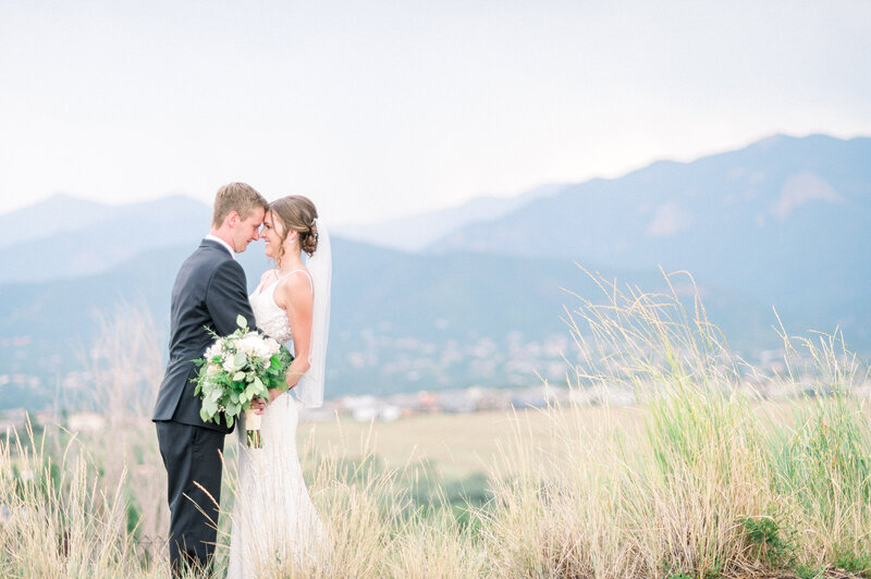 bride and groom embrace in front of mountain range in colorado springs