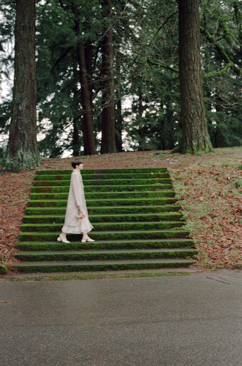 bride in Kamparett walking on the steps of mt tabor for her elopement