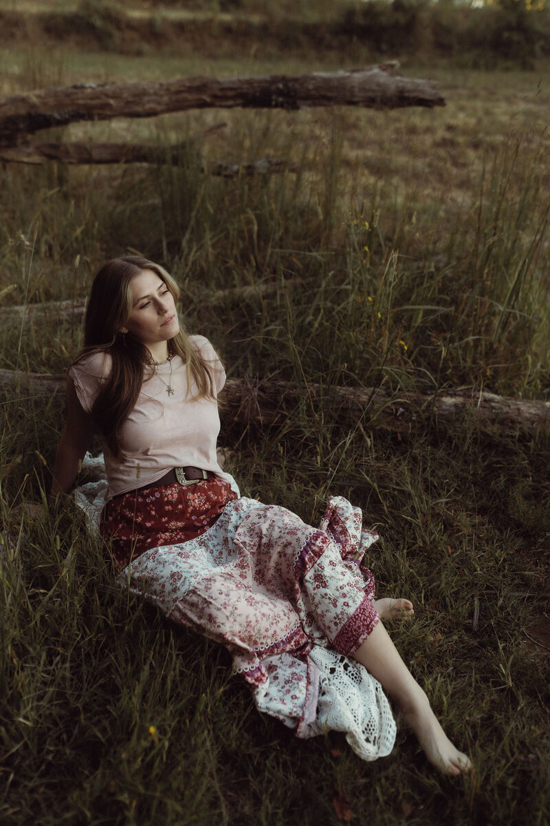 a woman in a quilted skirt sitting in a green field at golden hour. 
