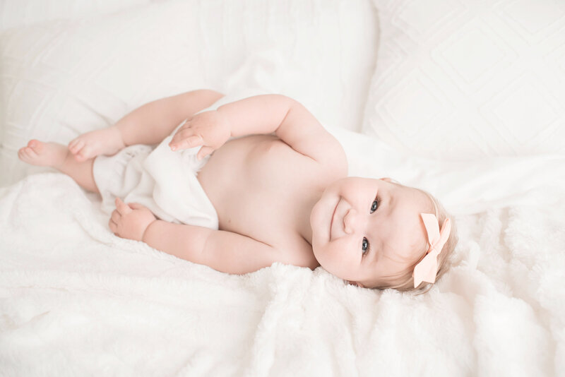 6 month old baby girl smiling on white blanket
