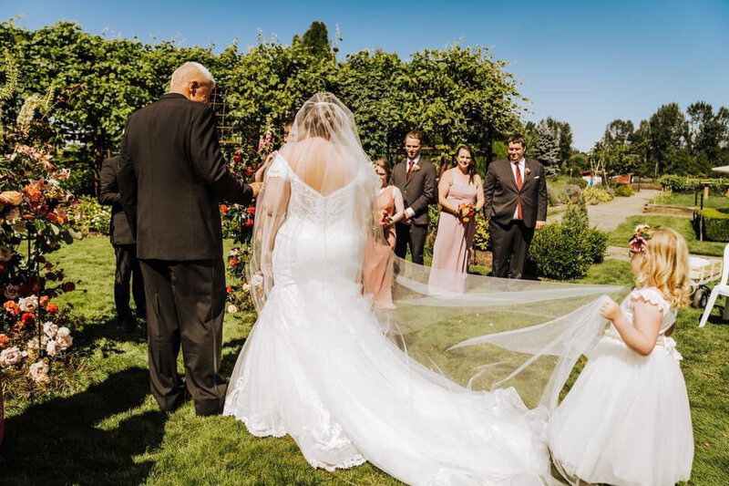 bride walking down the aisle in custom pearl bridal veil with father of the bride and flower girl