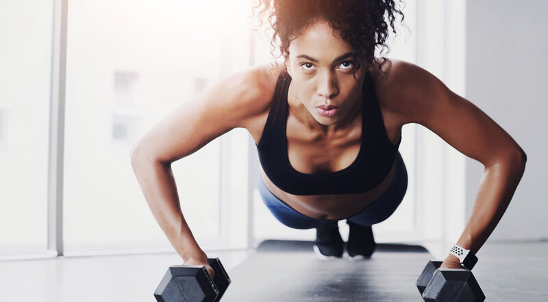 Woman doing pushups with dumbbells