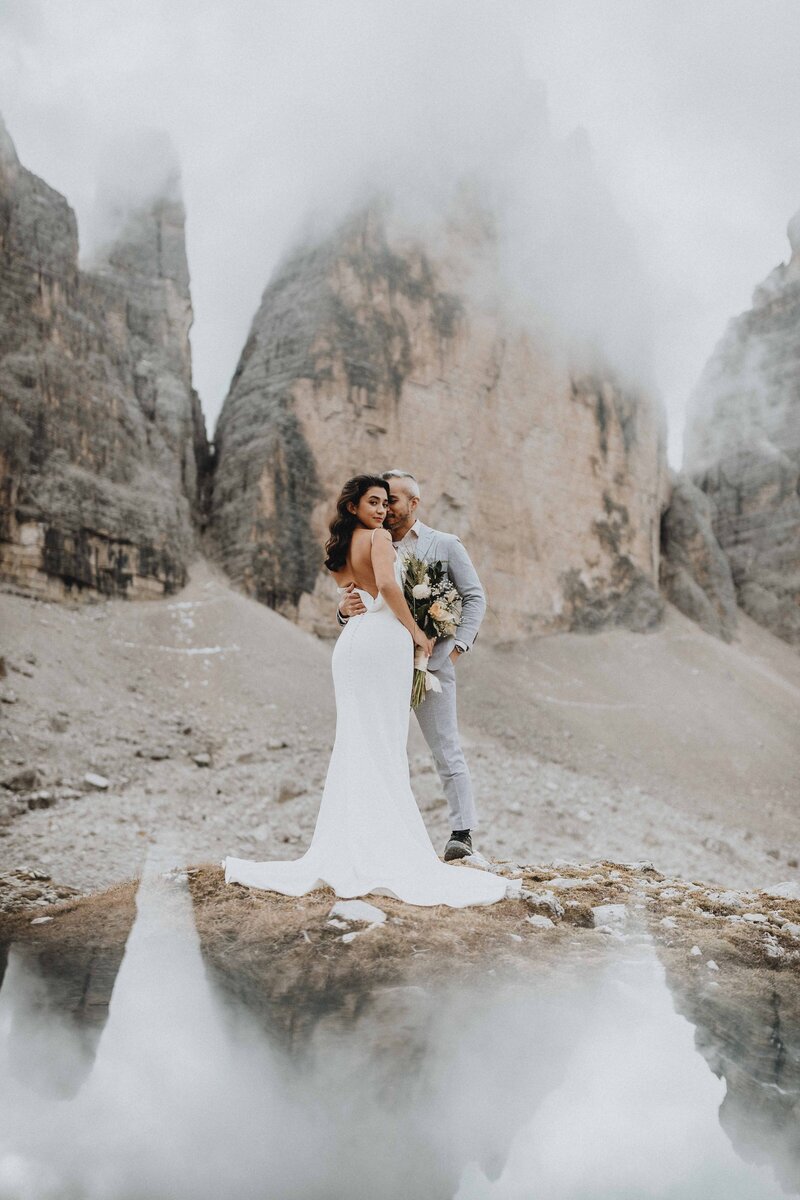 An eloping couple stands under the Tre Cime peaks in the Dolomites