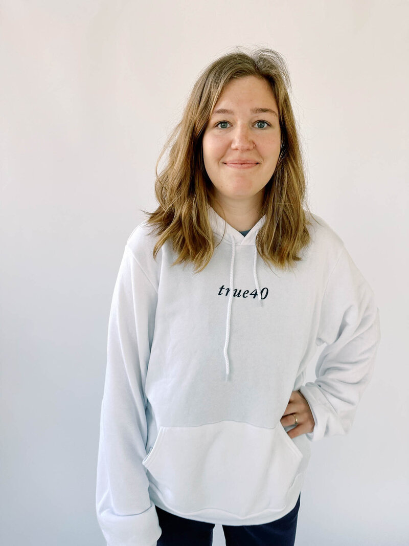 Woman wearing white unisex hoodie with true40 logo on the front