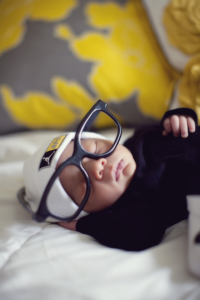 Newborn on his back with fake glasses on