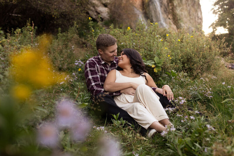 Couple laying together in a grassy Utah field during their session with Lamblight Photography