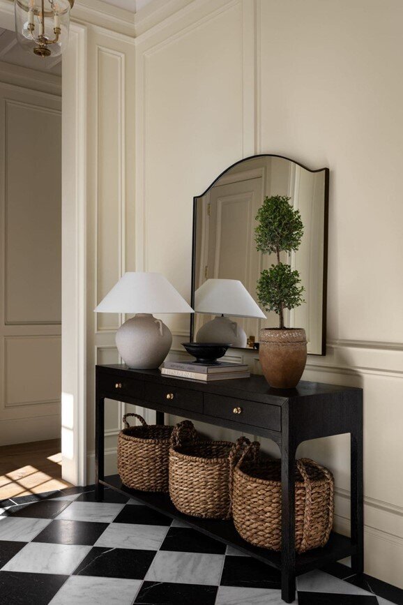 A black and white checkered floor featuring a mirror and two decorative baskets arranged nearby.