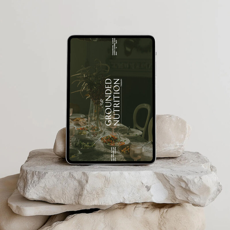 An iPad sitting on a rock displays a nutritionist website design and branding