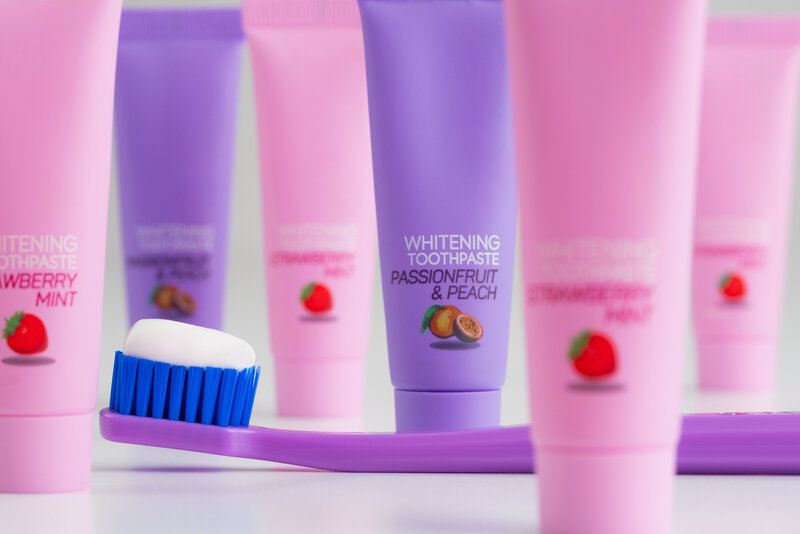 Different toothpaste tubes and a toothbrush with toothpaste on it