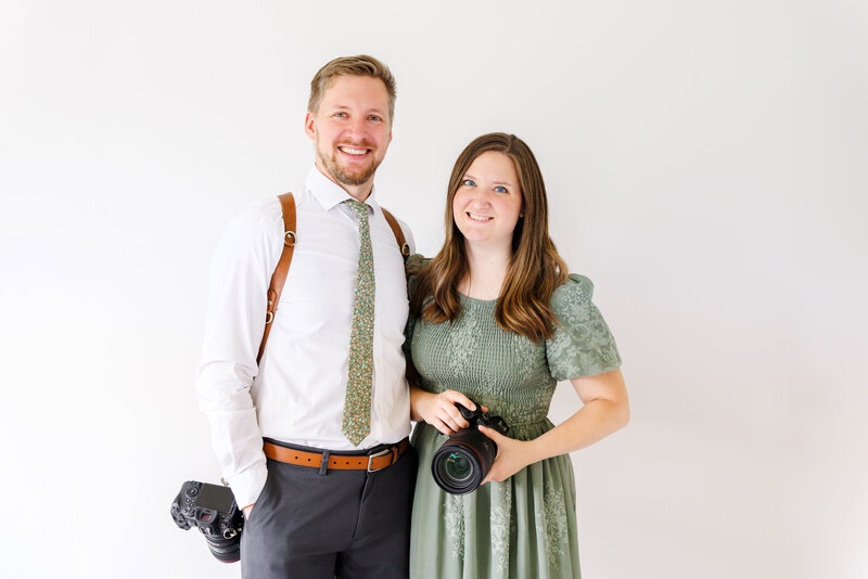 Jessie and Adam smiling while holding cameras