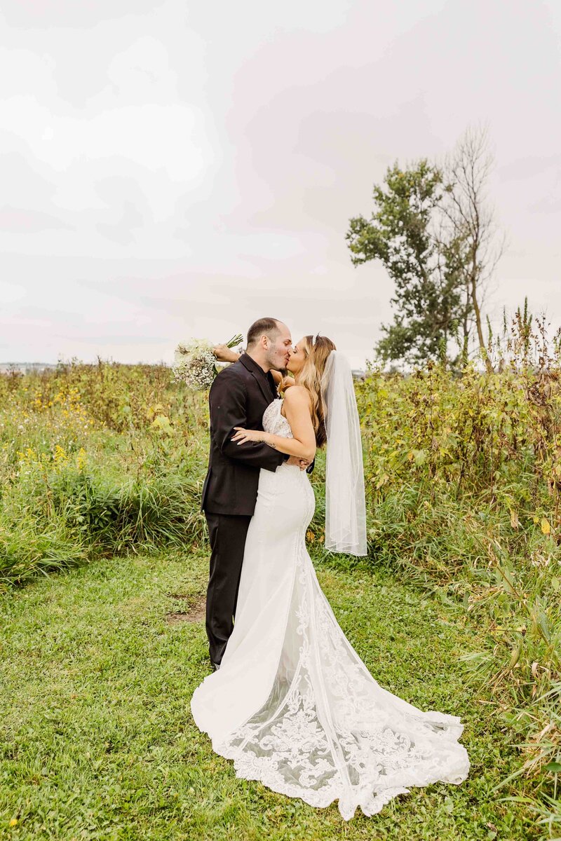 Bride and Groom Kiss in a field at Sugar Island Barn  in Wisconsin.