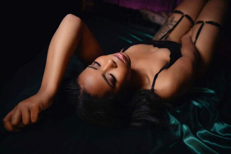 Dark skinned woman posing in low light boudoir portrait