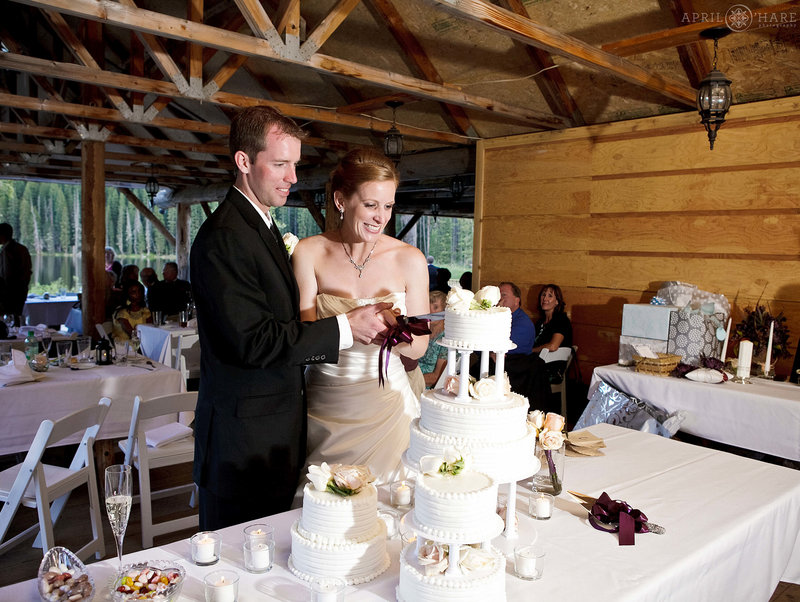 Cutting the cake in the outdoor covered reception space at Piney River Ranch