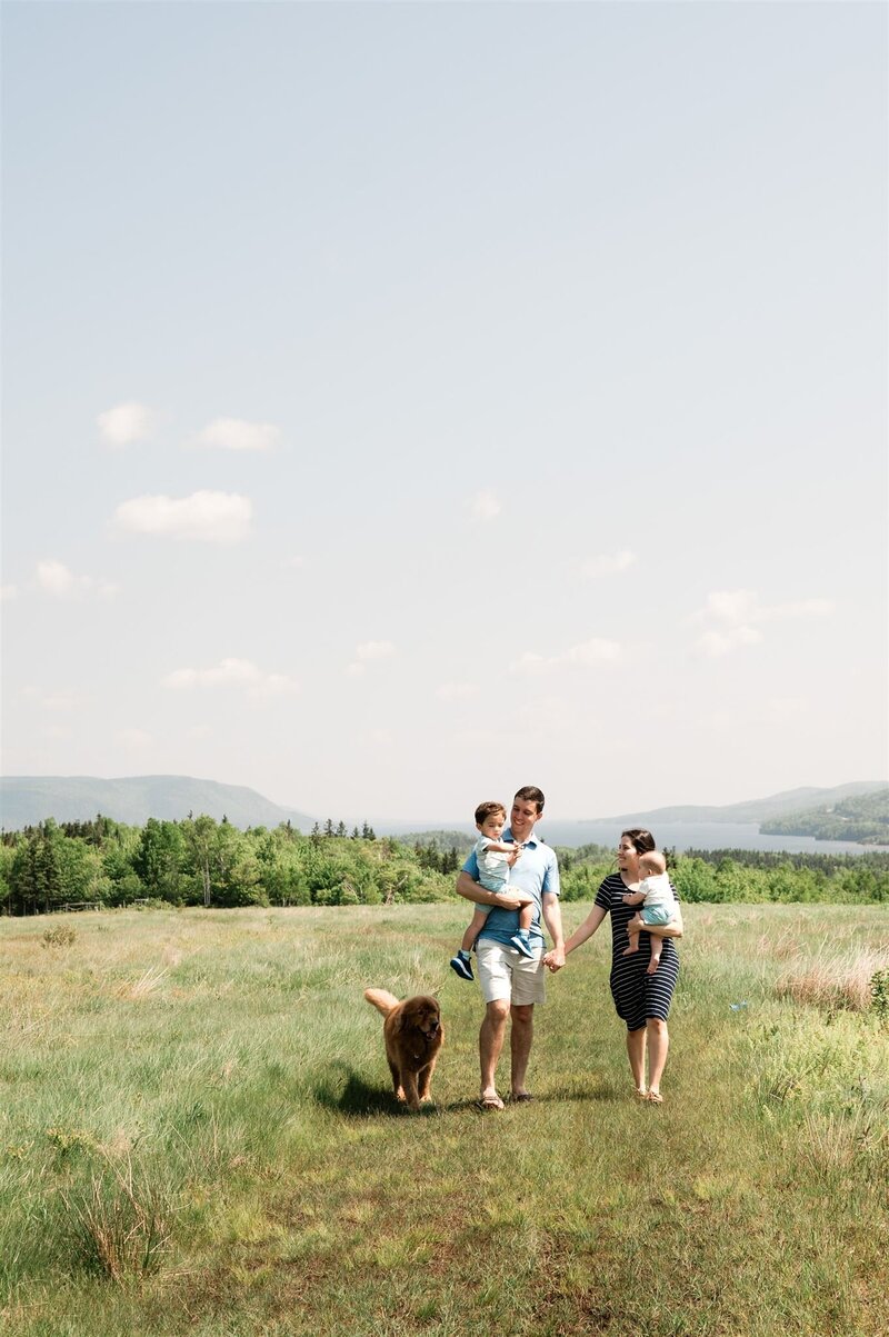 Family walking in a field for their family photo session in Cape Breton, Nova Scotia