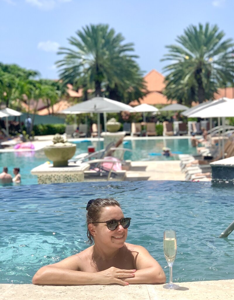 Woman in pool hot tub smiling with champagne glass to her side