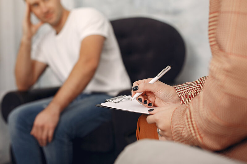 Close-up of a woman’s hands holding a pen, writing on a clipboard—representing anxiety therapy for high-functioning women.