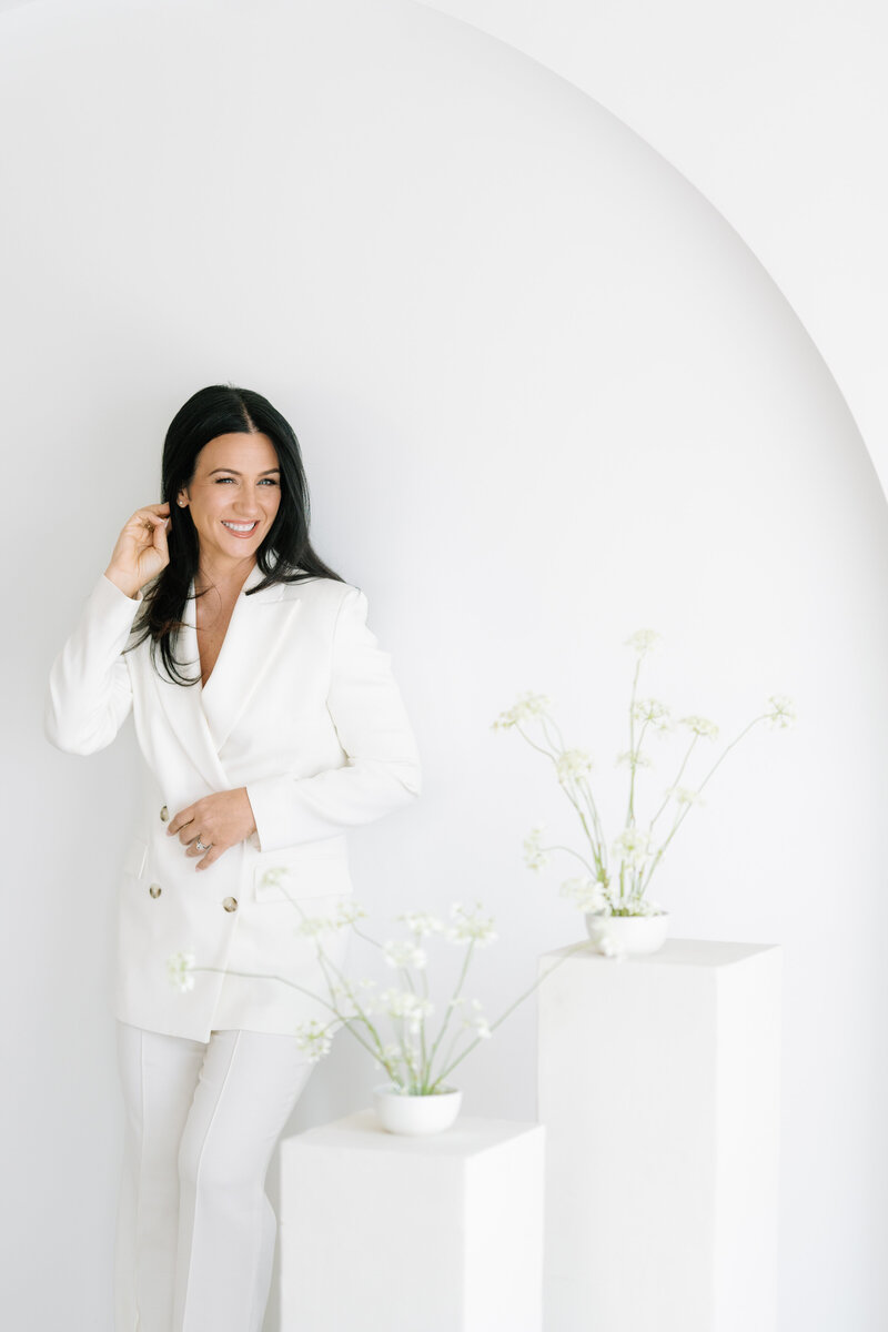 Vanessa Naumann, Las Vegas wedding planner, smiles for photo in chic white pantsuit