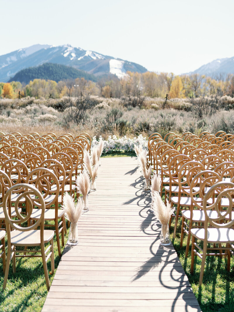 mountain view ceremony with wooden walkway, pampas grass, and helix chairs in October in Aspen