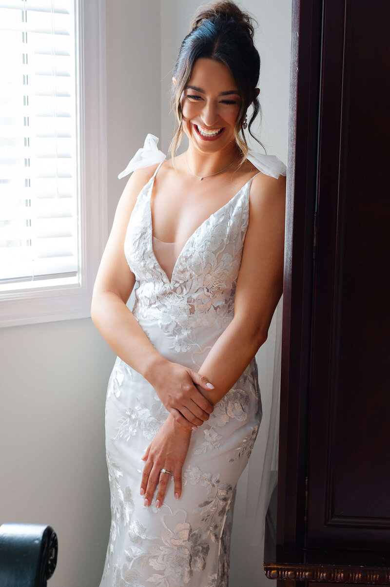 a photo of a bride leaning on her wardrobe smiling as she gets ready for her day.  Captured by Ottawa wedding photographer JEMMAN Photography