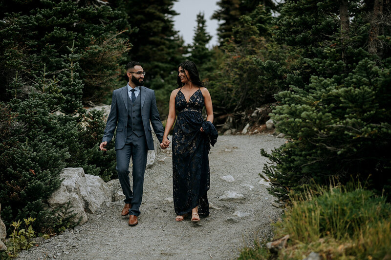 Bride and groom stand in snow in winter holding skis wearing heart shaped sunglasses