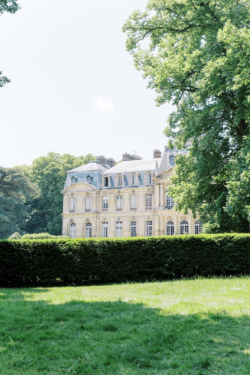 Château de Champlâtreux with green trees around taken by Wedding Photographer in Dallas
