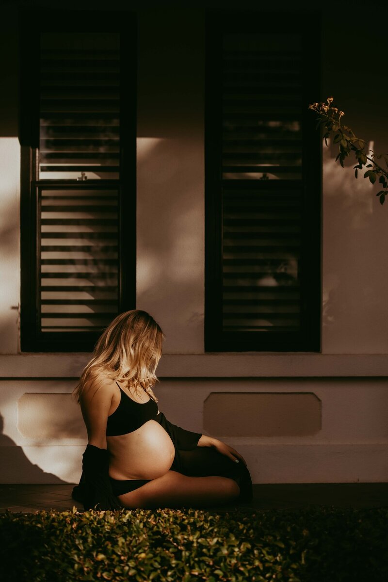 Expecting mother sitting outdoors in natural light, maternity photography in Sydney studio.