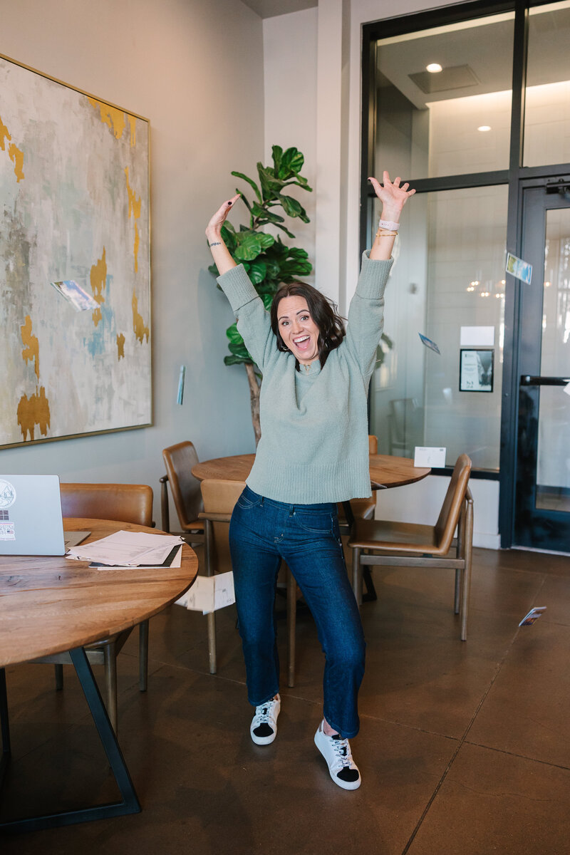 Jenn with her hands up in the air celebrating playfully