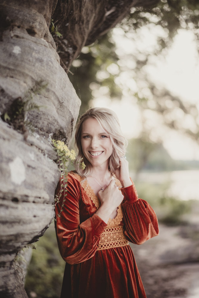 Caroline Weiss leaning against a rocky cliff, grounded and strong, representing resilience and healing.