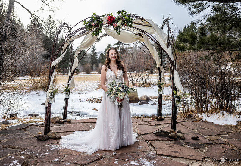 Bride on the Flagstone Patio next to the river at her winter wedding at Romantic Riversong Inn in Estes Park CO