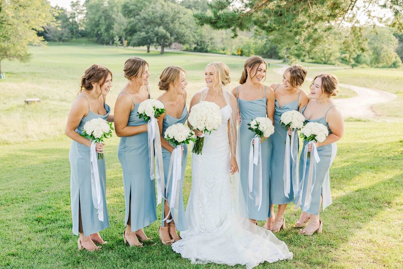 Bridesmaids in blue gowns laughing with bride at the Carriage House at Lac La Belle in Oconomowoc, Wisconsin.