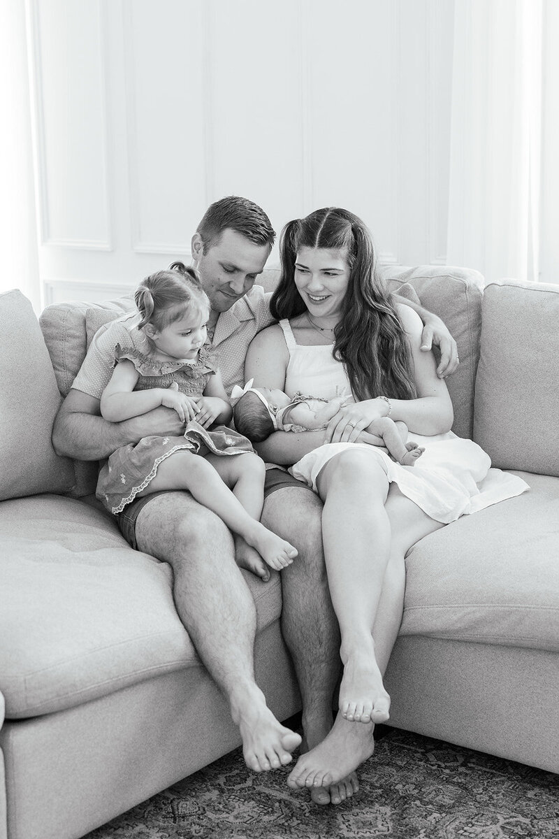 Family with toddler and newborn sitting on couch