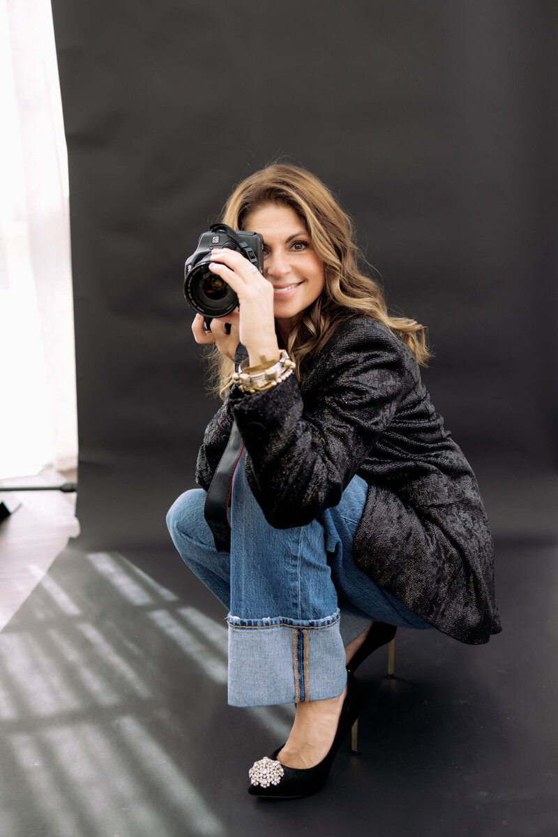 Kerri Link holds a camera and smiles softly, reflecting her creative spirit and passion for capturing authentic stories.