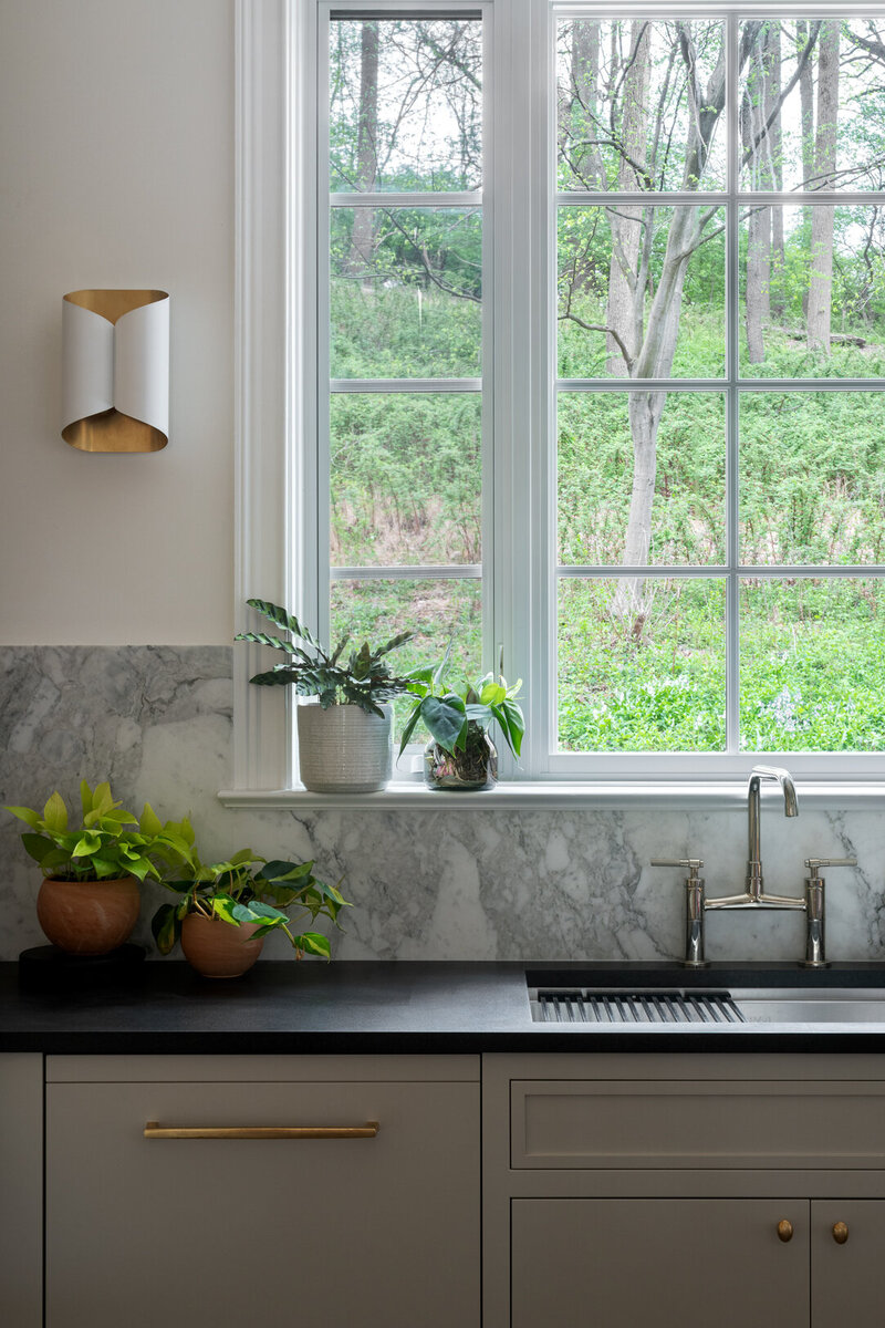 tan cabinets window overlooking grass with black countertops and sink