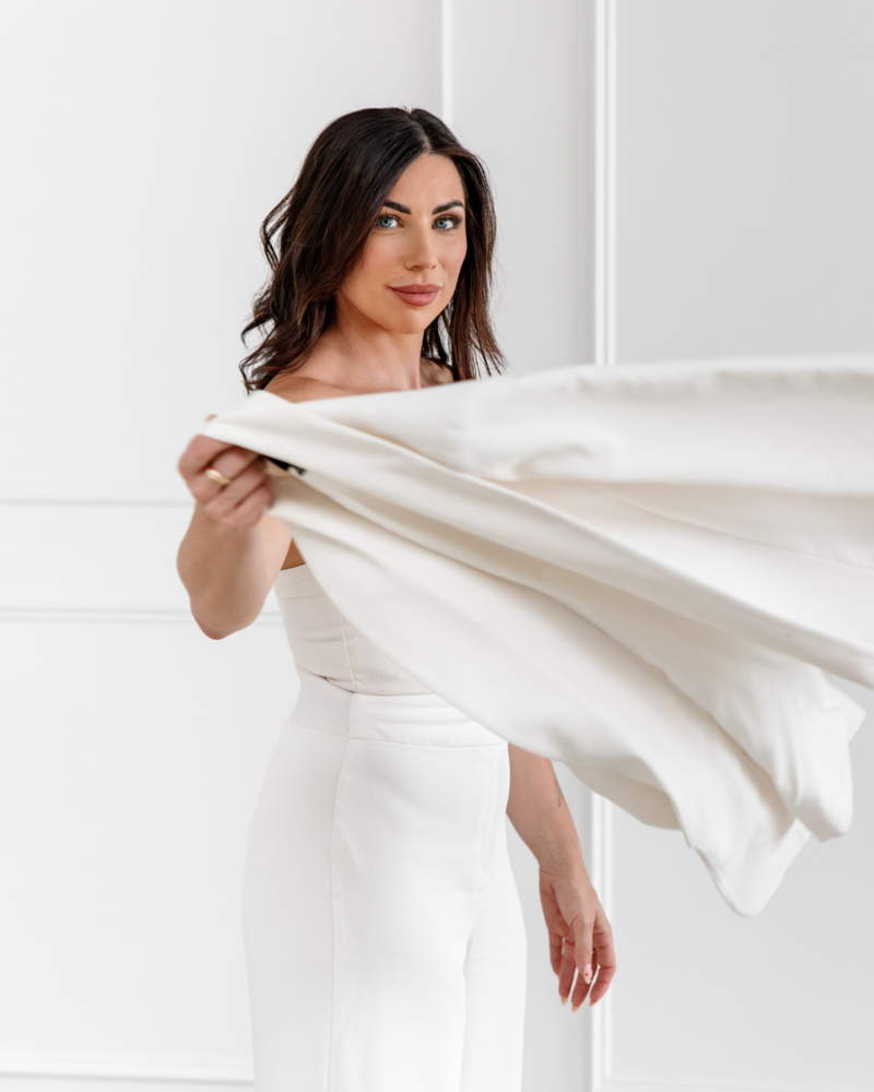 Woman throwing a white blazer over her shoulder
