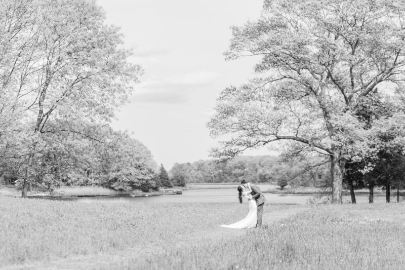 bride and groom kissing in a field