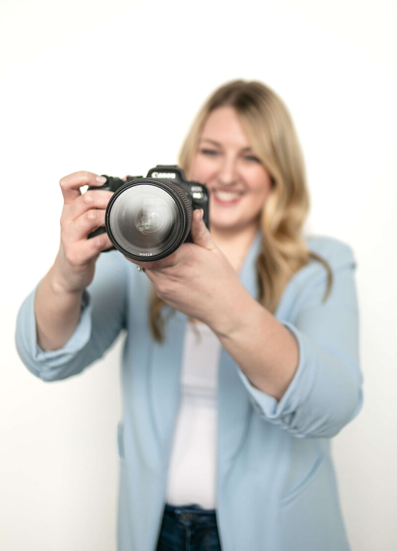 Woman with blonde hair smiling and holding a camera