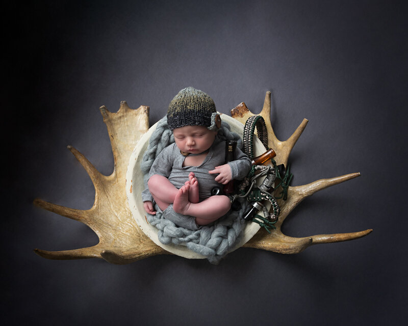 A tribute to heritage and the outdoors—this newborn portrait features a hunting-inspired antler setup and rustic textures.